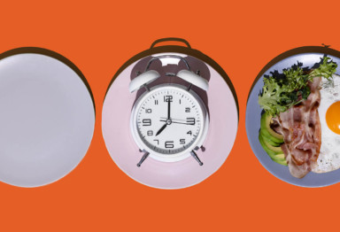 Plate, clock and breakfast food laid out on orange table
