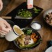 Person pouring sauce on plate full of meat and veggies
