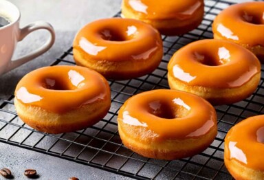 Espresso donuts on a cooling rack next to a mug of coffee.