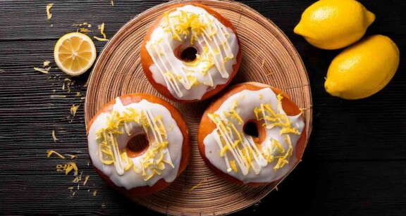 Overhead view of lemon ginger donuts on a round tray with surrounding lemon accents.