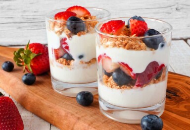 Yogurt parfaits made with berries and granola on wood serving tray