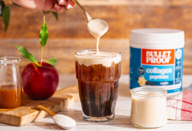 Cold brew coffee in glass with freshly made caramel apple cold foam being poured on top