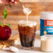 Cold brew coffee in glass with freshly made caramel apple cold foam being poured on top