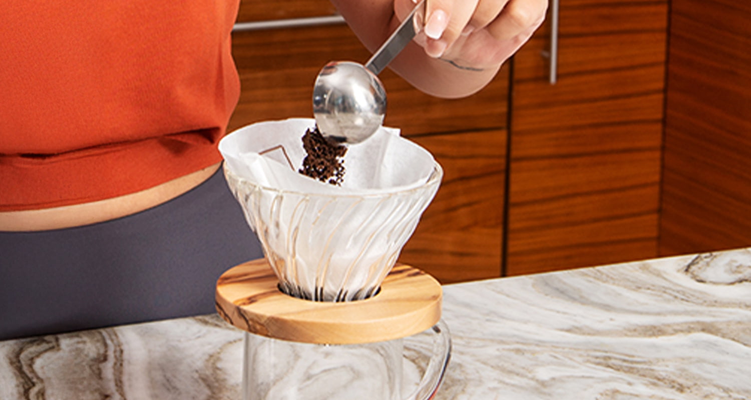 person adding coffee to pour over