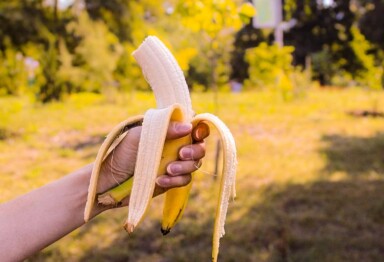 Hand holding peeled banana in a forest