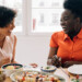 two women laughing while enjoying a meal together