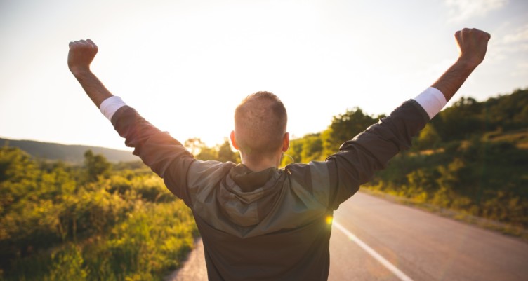 man raising arms in air outside