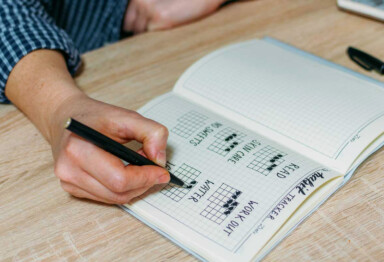 Male writing down and tracking their healthy habit tracker at their desk