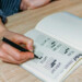 Male writing down and tracking their healthy habit tracker at their desk