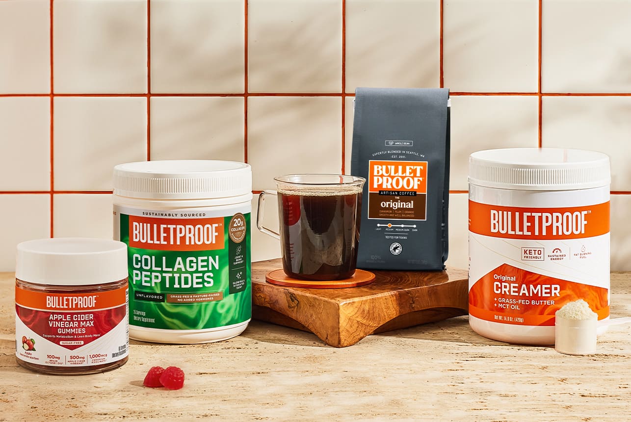 Bulletproof gummies, collagen peptides, ground coffee, and enhanced creamer on counter with tile background
