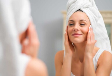 Woman touching her face while looking in mirror