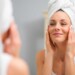 Woman touching her face while looking in mirror